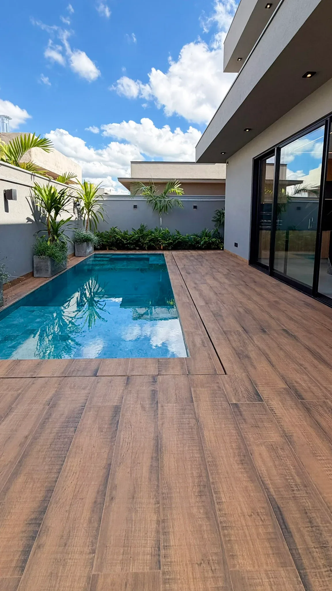 Piscina com deck e paisagismo junto à área gourmet.